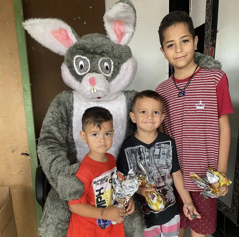 Coelho da Páscoa com crianças recebendo ovos de chocolate